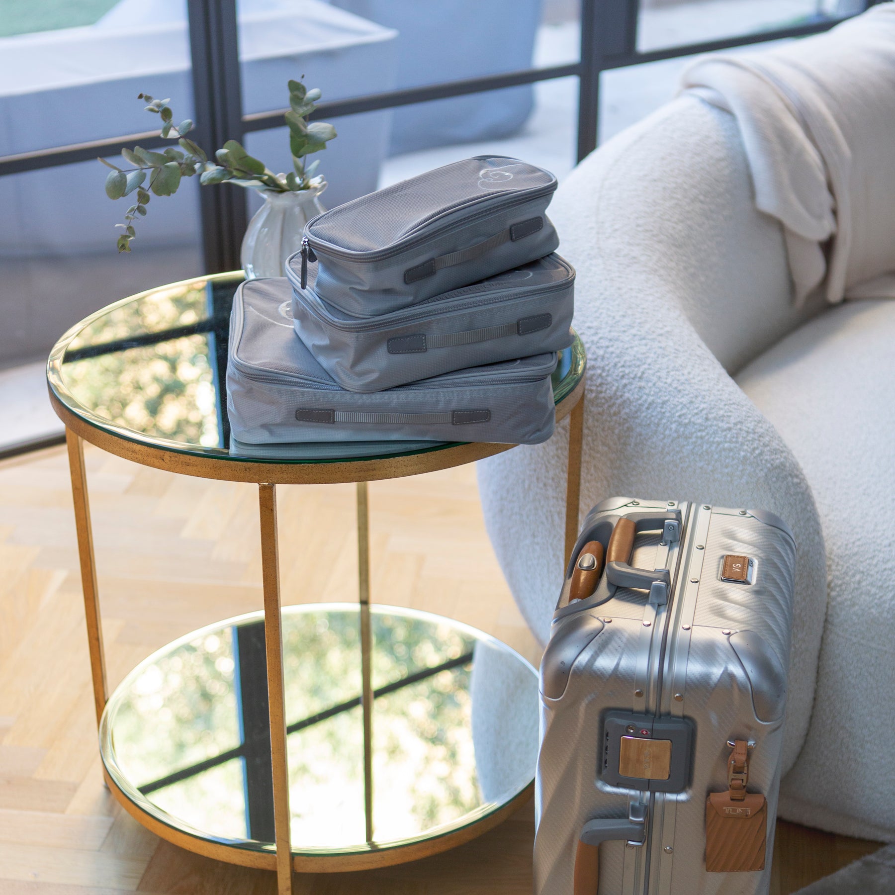 Stacked travel packing cubes on top of mirrored glass table
