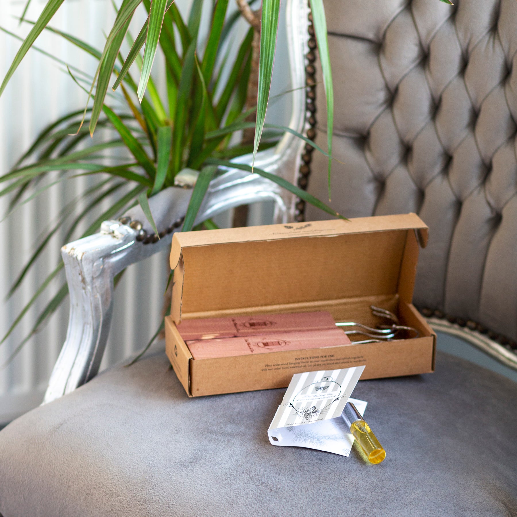 Cedarwood essential oil refresher spray on plush seating beside open box containing cedarwood hanging blocks