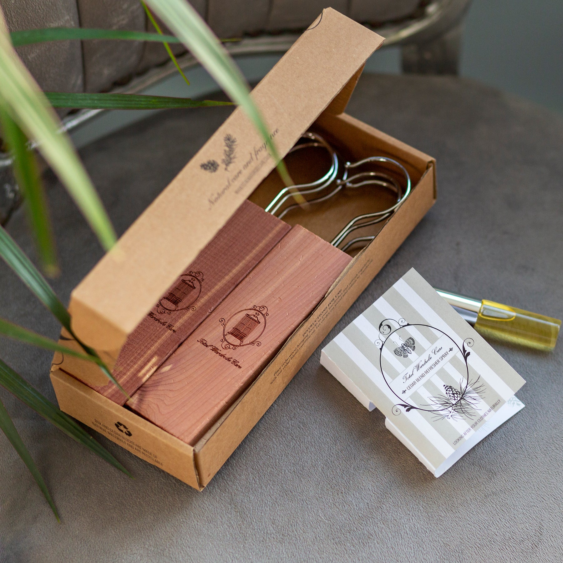 Open cardboard packaging for cedarwood hanging blocks on dark table with essential oil refresher spray to side