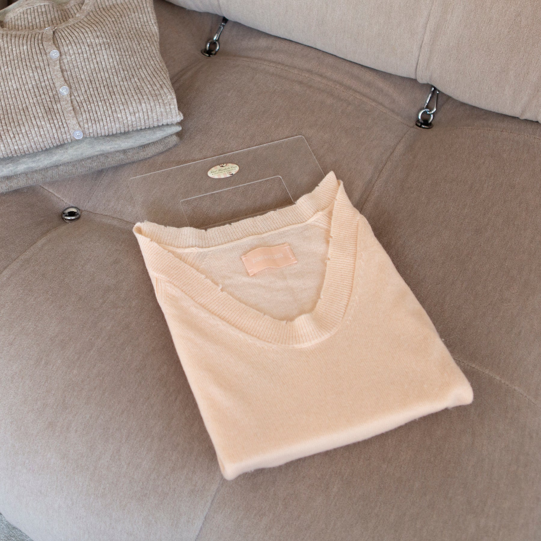 Folding palette with peach jumper resting on plush sofa