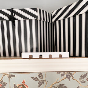 Black and white storage boxes to top of wardrobe with moth box in front