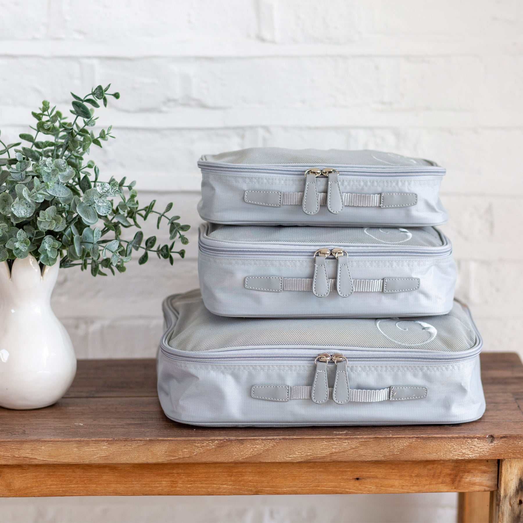 Stacked travel packing cubes on wooden table