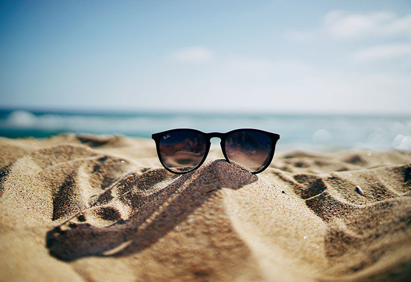Pair of sunglasses on sandy beach