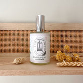 Small bottle of May Chang linen spray stood on sideboard with wheat beside