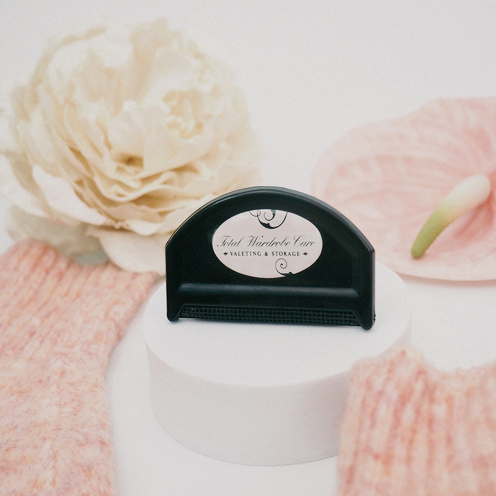 Knitwear comb on white circular pedestal beside flowers