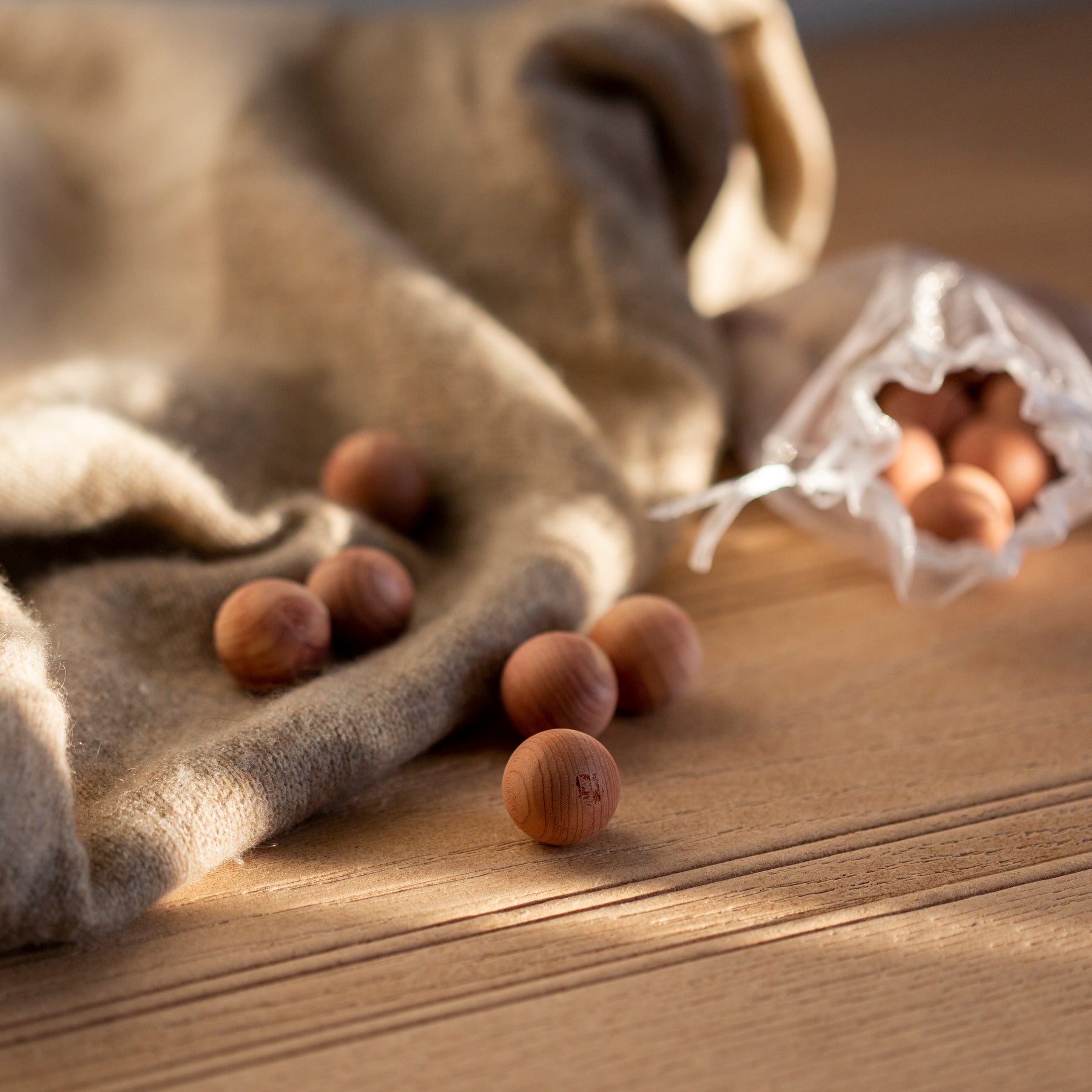 Loose cedarwood balls on wooden surface with tussled cashmere jumper