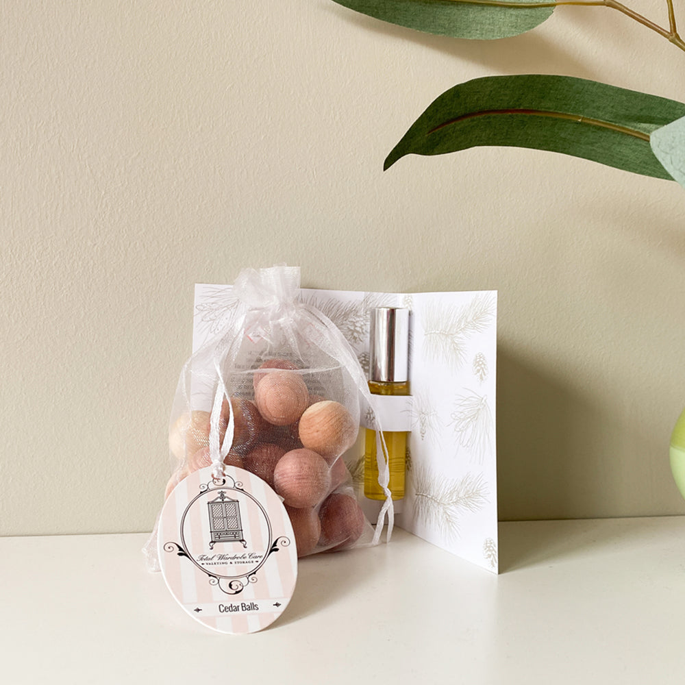 Open refresher spray packaging with organza bag of cedarwood balls beside green plant