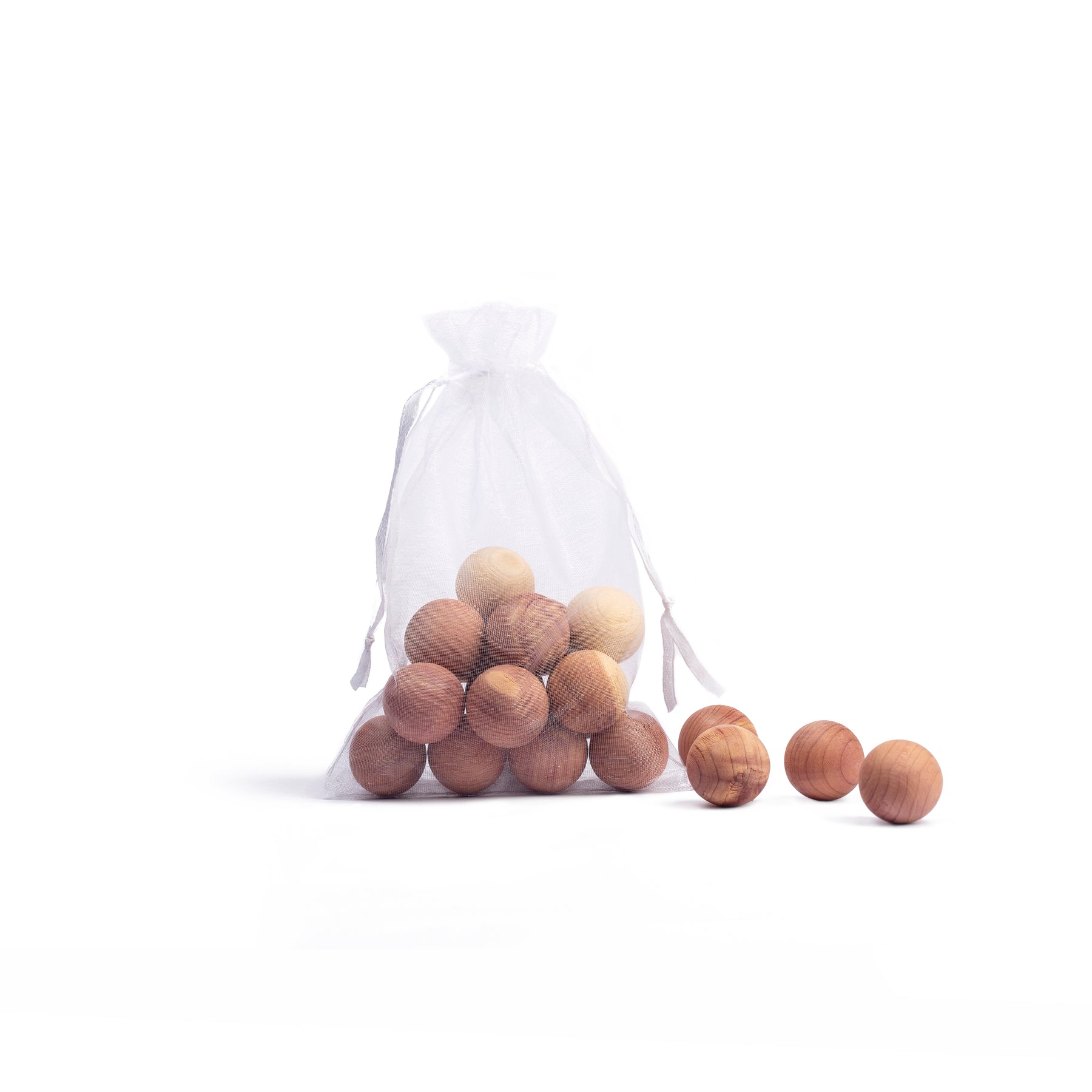 Small see through bag with canada red cedarwood balls with 4 balls separate on white background