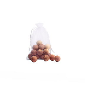 small fabric bag containing canada red cedar balls with 4 loose from bag on white background