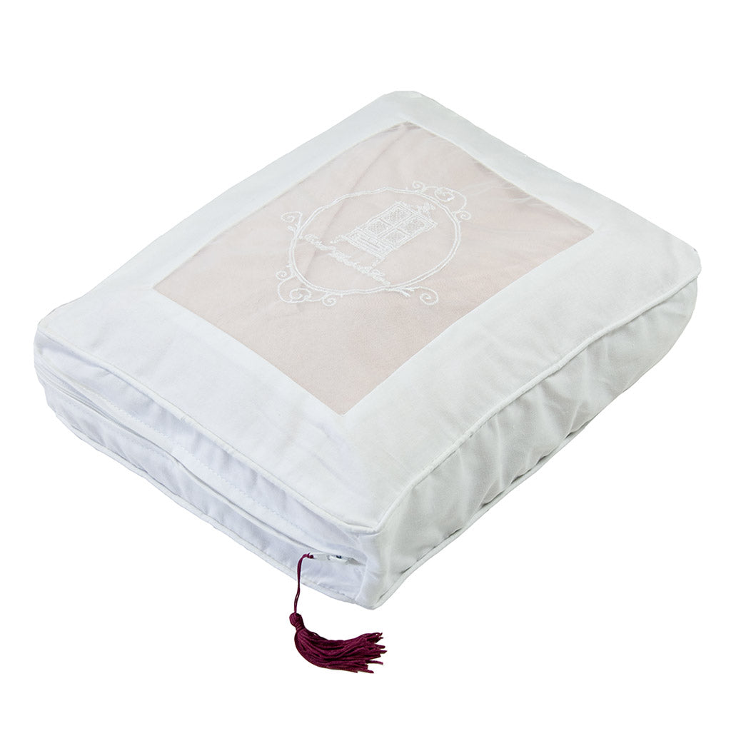 Cashmere storage bag with burgundy tassel resting on bright white background