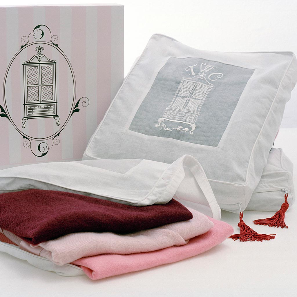 3 Cashmere storage bags containing red and pink cashmere on white surface