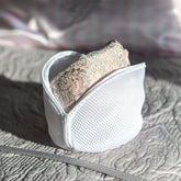 Open netted lingerie wash bag on textured bedspread