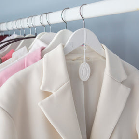 White wooden hanger holding light coloured blazer and white ceramic infuser