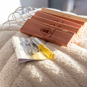 Row of cedarwood hanging blocks laying on top of plush fabric with small refresher spray alongside