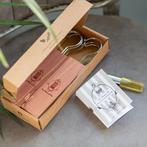 Open box containing cedarwood hanging blocks on fabric seat beside cedarwood refresher spray