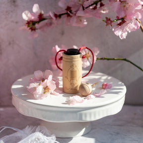 Wooden diffuser cup with bottle of May Chang essential oil inside surrounded by cherry blossom