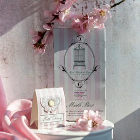 Standing Moth Box and Moth Decoy on circular white table surrounded by cherry blossoms