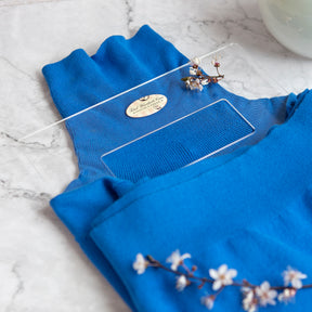 Blue turtle neck folded on folding palette on white marble surface with small white flowers present