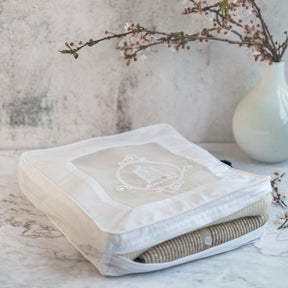 Cashmere storage bag open on marble surface with vase of cherry blossoms 