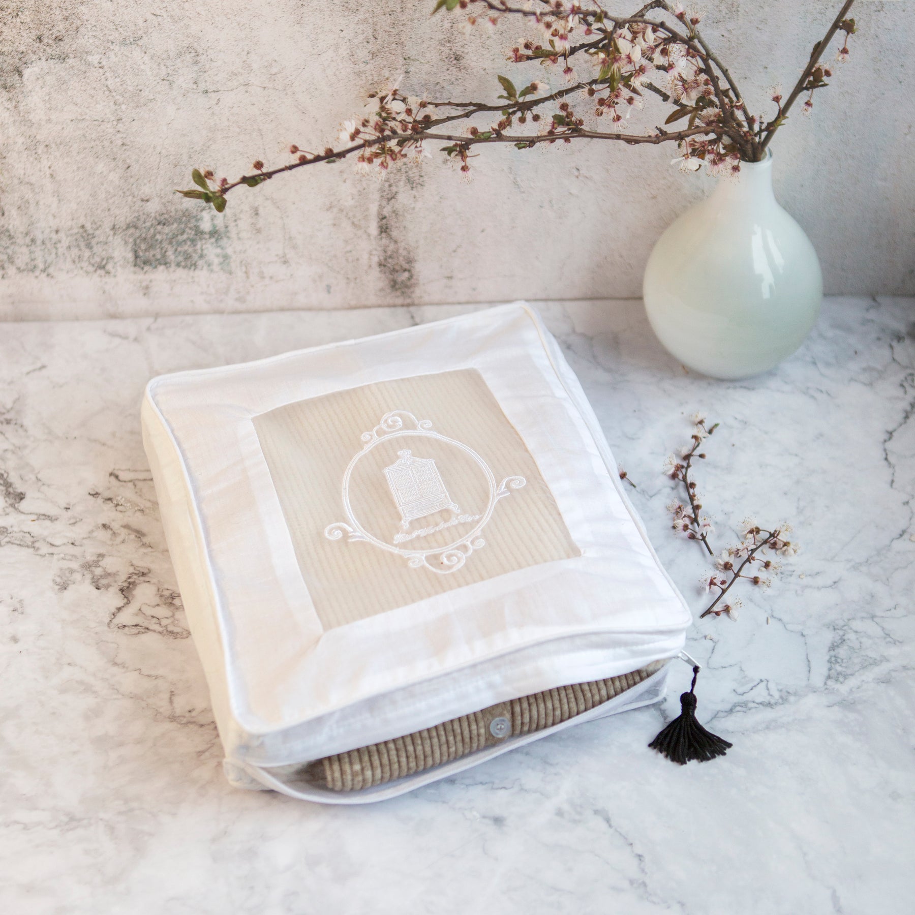 Cashmere storage bag on marble surface with black tassel and cherry blossoms to reverse
