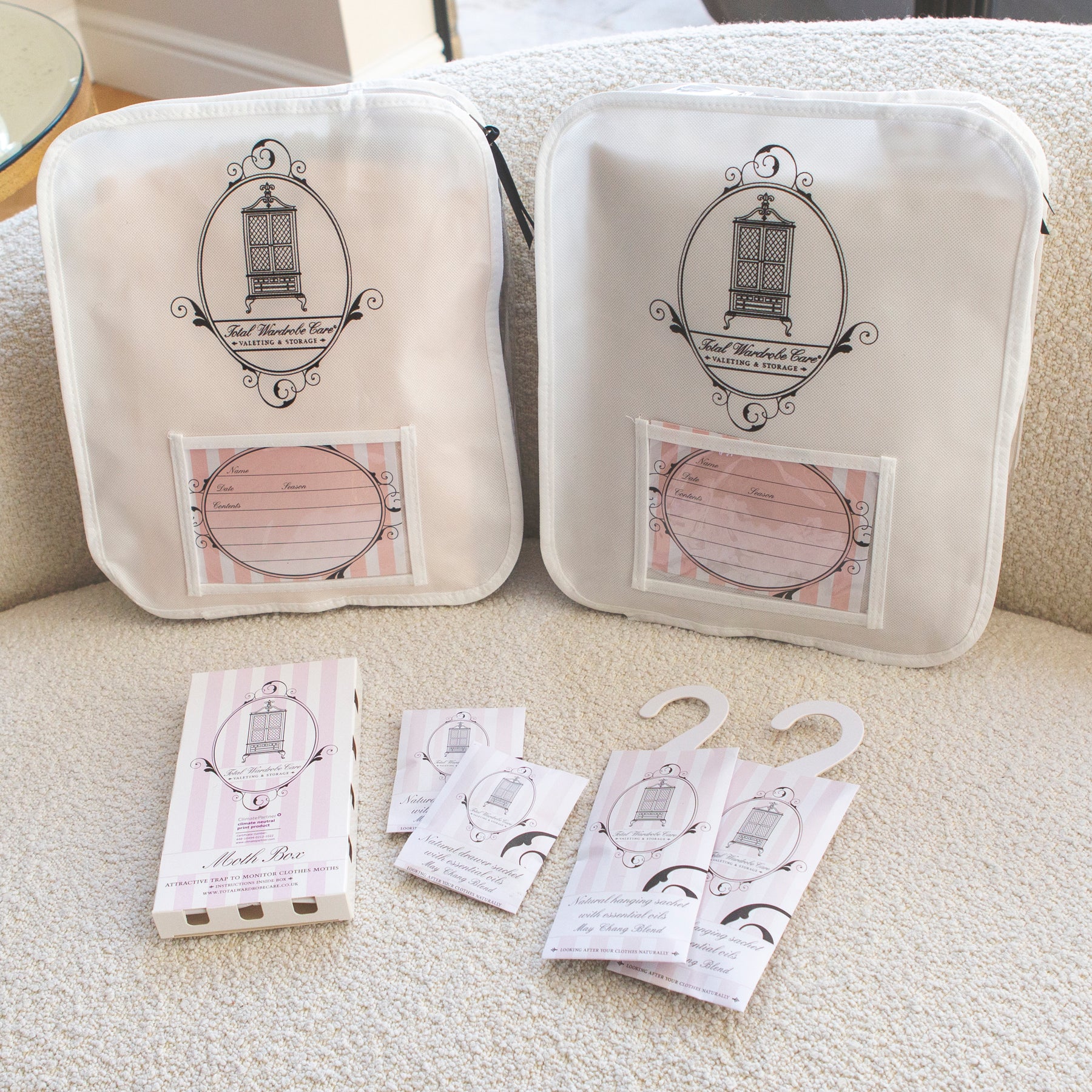 Total Wardrobe Care moth box, hanging and drawer sachets beside knitwear storage bags on fabric surface