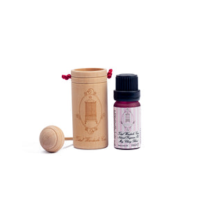 Pink packaged may chang essential oil beside wooden diffuser cup on white background