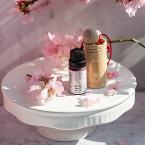 May chang essential oil and wooden diffuser on ceramic table surrounded by pink flower